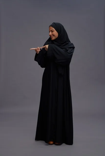 امرأة سعودية بعباءة سوداء تشير في الاستوديو