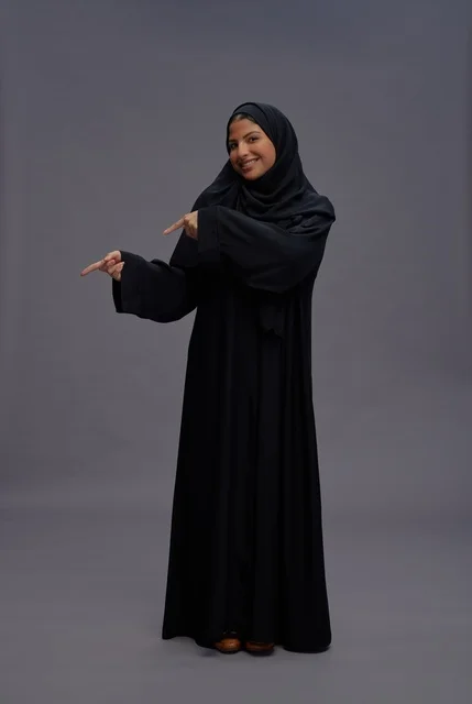 Saudi Woman in Abaya Pointing on Grey Background