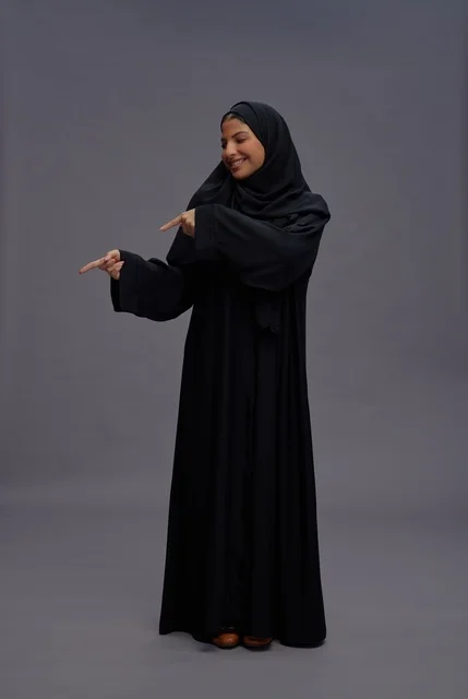 امرأة سعودية بالعباءة السوداء تشير في الاستوديو