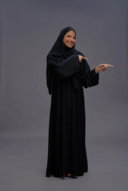 امرأة سعودية بالعباءة تشير في الاستوديو