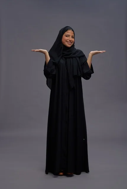 امرأة سعودية بعباءة سوداء في وضعية عرض بالاستوديو