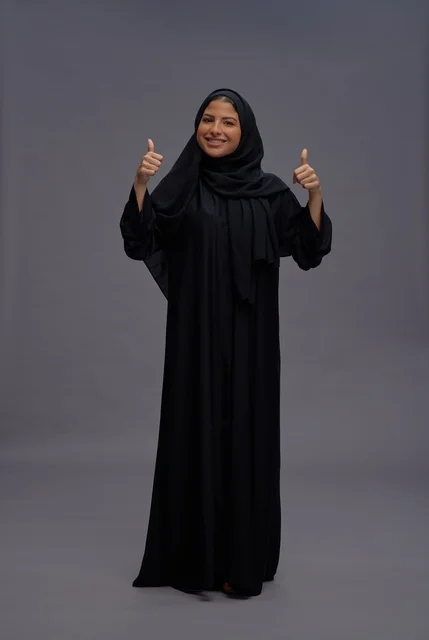 امرأة سعودية بالعباءة السوداء التقليدية تشير بالإبهام
