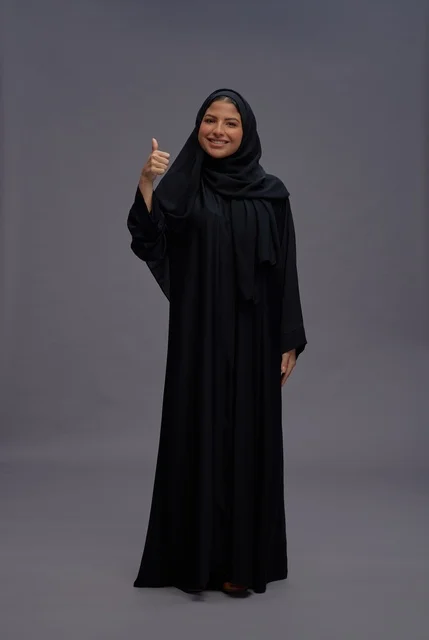 امرأة سعودية بالعباءة السوداء تعطي إشارة الإبهام للأعلى