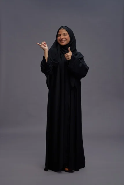 امرأة سعودية بالعباءة السوداء تشير بعلامة الإعجاب
