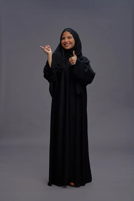 امرأة سعودية بعباءة سوداء مع إيماءة الإبهام للأعلى