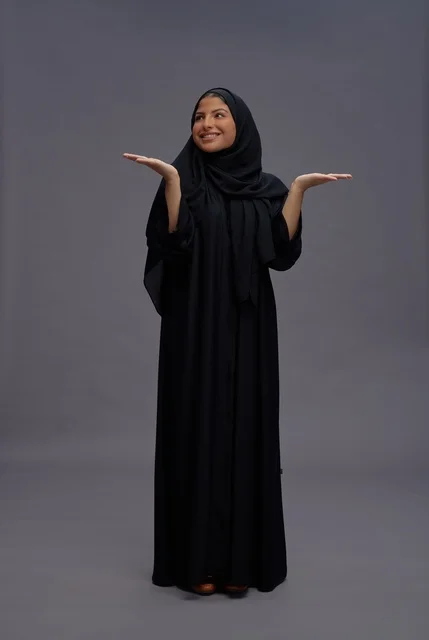 امرأة سعودية بالعباءة السوداء مع إيماءة تقديم