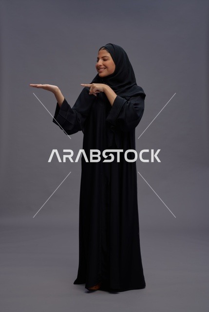 امرأة سعودية بالعباءة السوداء في وضعية عرض تقديمي
