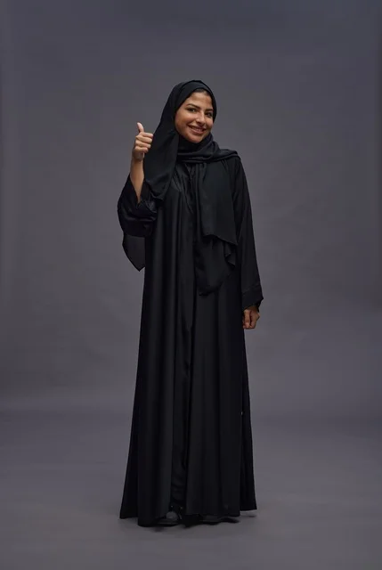 امرأة سعودية بالعباءة السوداء تشير بالإبهام للأعلى