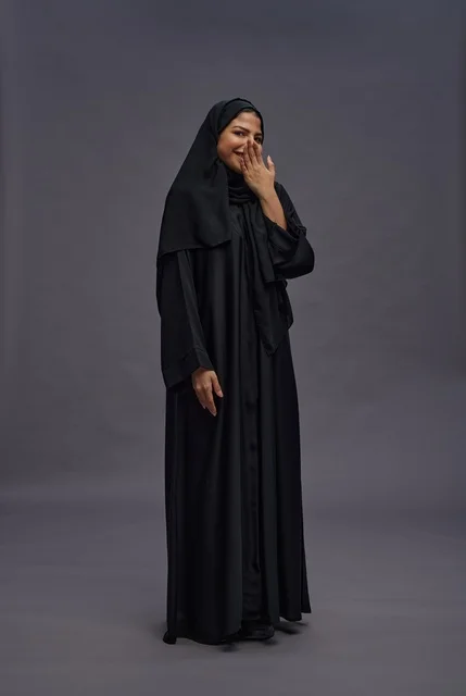 امرأة سعودية بعباءة سوداء تضحك في الاستوديو امرأة سعودية بعباءة سوداء تضحك في الاستوديو