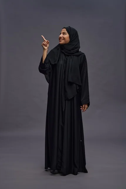 امرأة سعودية بالعباءة السوداء تشير في الاستوديو