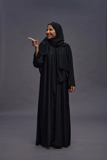 امرأة سعودية بعباءة سوداء تشير في استوديو
