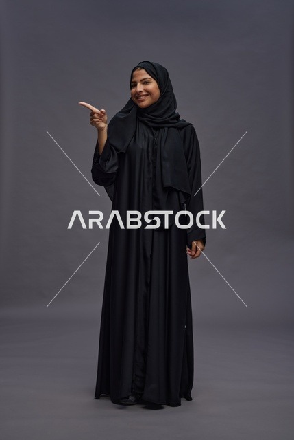 Saudi Woman in Abaya Pointing on Gray Background