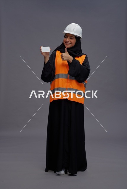مهندسة عربية تحمل بطاقة بيضاء مع إيماءة الإبهام