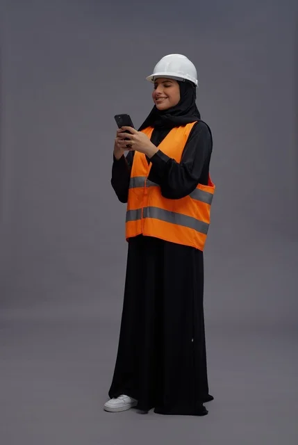 Saudi Female Engineer Using Smartphone in Safety Gear