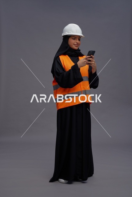 مهندسة سعودية بملابس السلامة تستخدم الهاتف الذكي
