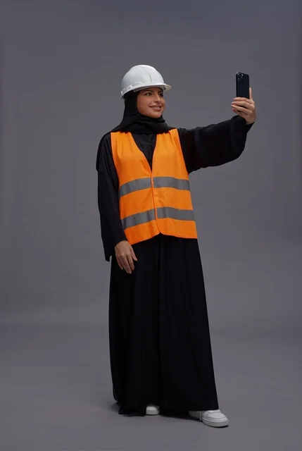 مهندسة سعودية في سترة السلامة مع هاتف ذكي