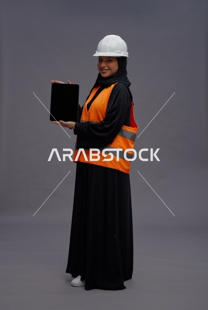 مهندسة سعودية تحمل جهاز لوحي بسترة السلامة