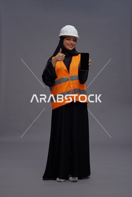 مهندسة سعودية مع هاتف ذكي وإيماءة الإبهام