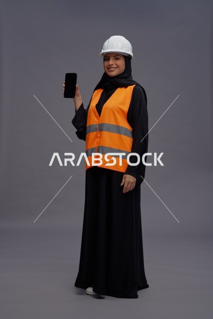 مهندسة عربية تحمل هاتف ذكي بملابس العمل المهنية