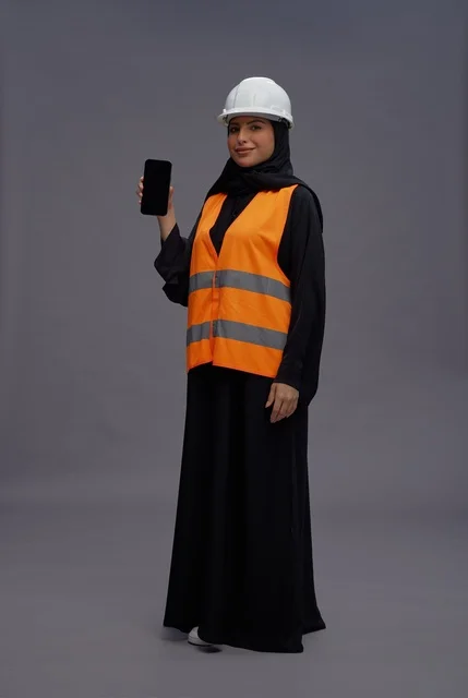 مهندسة سعودية تمسك هاتف ذكي بمعدات السلامة