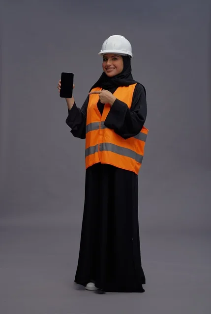 Saudi Female Engineer Holding Smartphone in Safety Gear