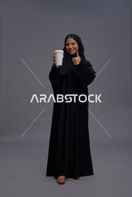 امرأة سعودية بعباءة سوداء تحمل كوب قهوة