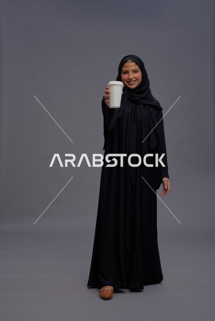 امرأة سعودية بعباءة سوداء تحمل كوب قهوة
