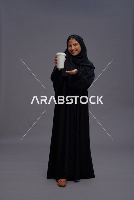 امرأة سعودية بعباءة سوداء تحمل كوب قهوة