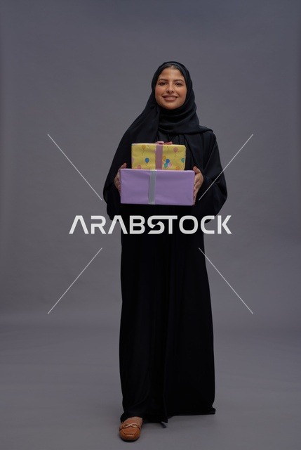 امرأة سعودية بعباية سوداء تحمل صناديق هدايا