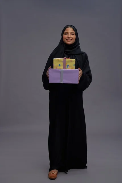 امرأة سعودية بعباية سوداء تحمل صناديق هدايا