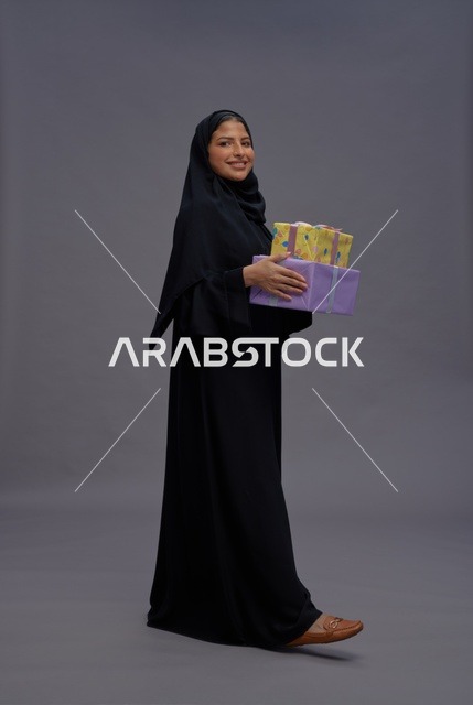 امرأة سعودية بعباية سوداء تحمل صناديق هدايا ملونة