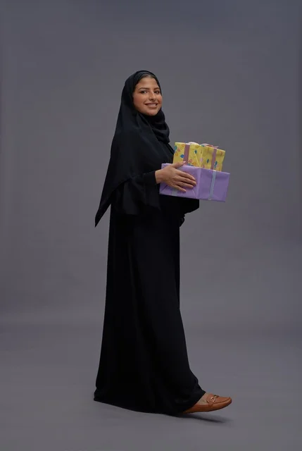 امرأة سعودية بعباية سوداء تحمل صناديق هدايا ملونة امرأة سعودية بعباية سوداء تحمل صناديق هدايا ملونة
