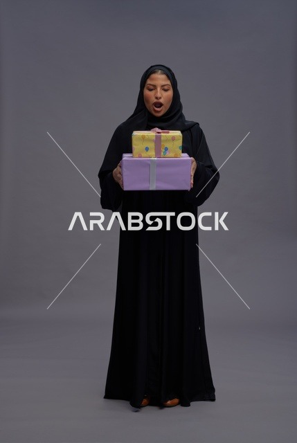 امرأة سعودية بالعباية السوداء تحمل علب هدايا
