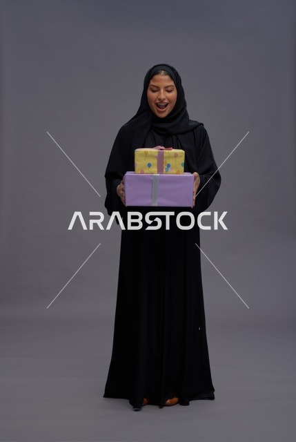 امرأة سعودية بعباية سوداء تحمل هدايا احتفالية