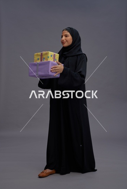 امرأة سعودية بعباية سوداء تحمل صناديق هدايا