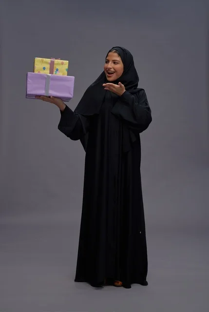 امرأة سعودية بعباية سوداء تحمل صناديق هدايا