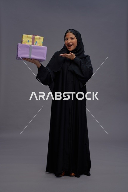 امرأة سعودية بعباية سوداء تحمل هدايا ملونة