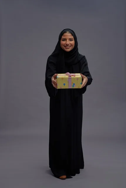 امرأة سعودية بعباية سوداء تحمل علبة هدية