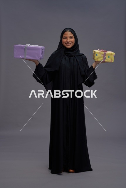 امرأة سعودية بعباية سوداء تحمل صناديق هدايا