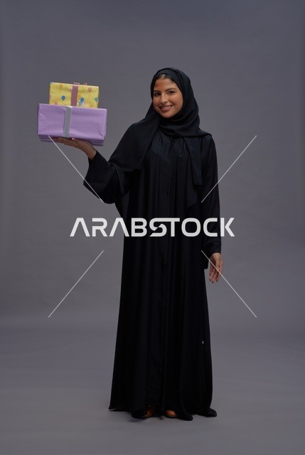امرأة سعودية بالعباية السوداء تحمل علب هدايا