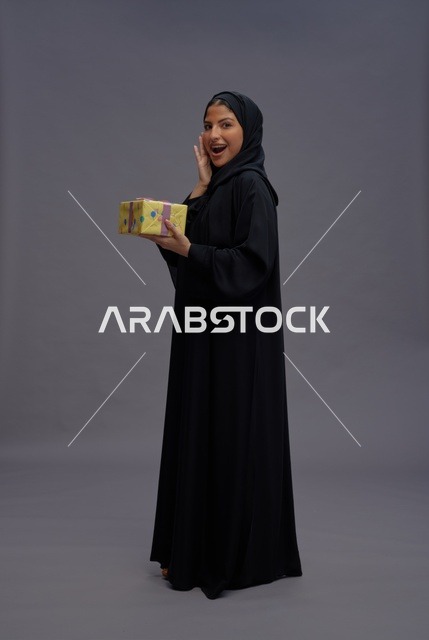 امرأة سعودية بعباية سوداء تحمل علبة هدية