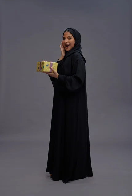امرأة سعودية بعباية سوداء تحمل علبة هدية