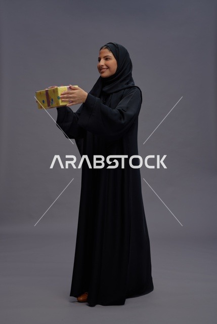 امرأة سعودية بعباية سوداء تحمل علبة هدايا