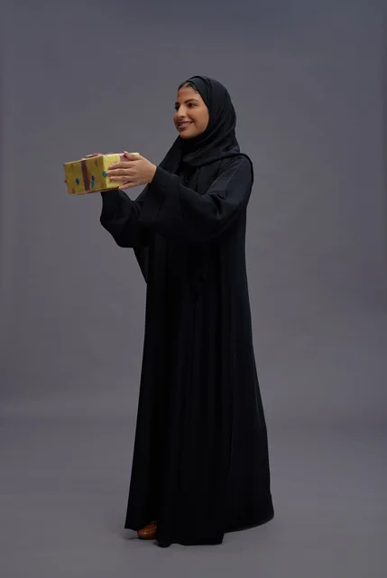 امرأة سعودية بعباية سوداء تحمل علبة هدايا