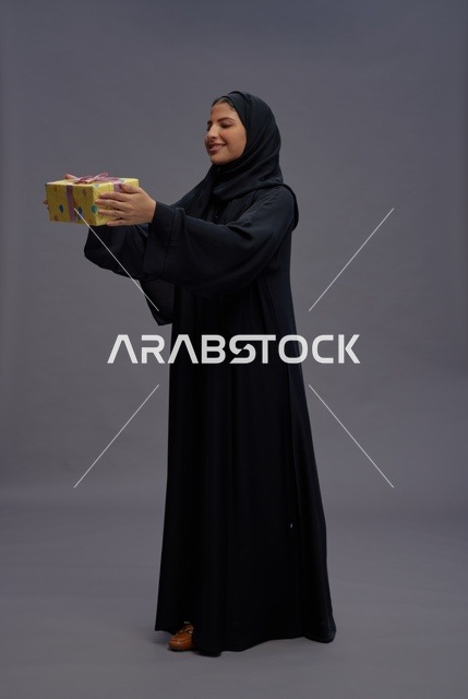 امرأة سعودية بعباية سوداء تحمل علبة هدية