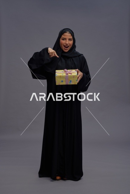 امرأة سعودية بعباية سوداء تحمل علبة هدية
