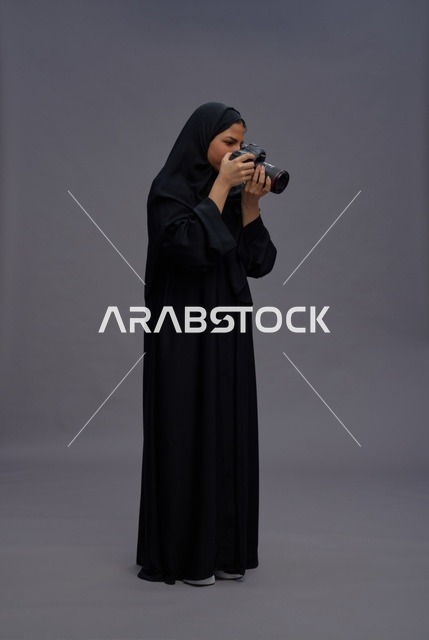 امرأة سعودية تحمل كاميرا احترافية في استوديو