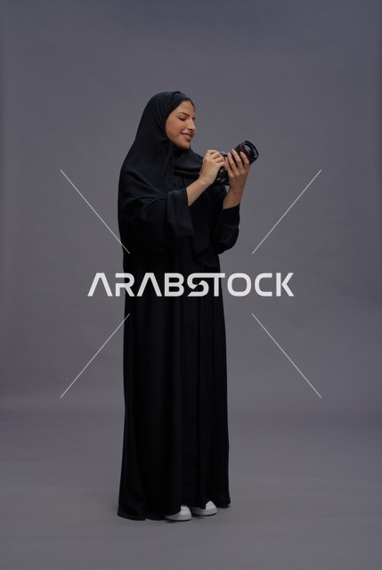 امرأة سعودية بالعباءة تمسك بكاميرا احترافية