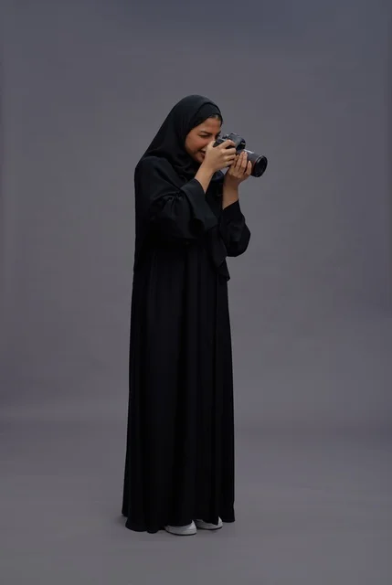 Saudi Woman in Abaya Holding Professional DSLR Camera Saudi Woman in Abaya Holding Professional DSLR Camera