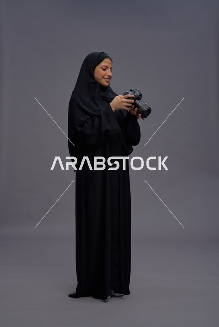امرأة سعودية بالعباءة تمسك بكاميرا احترافية